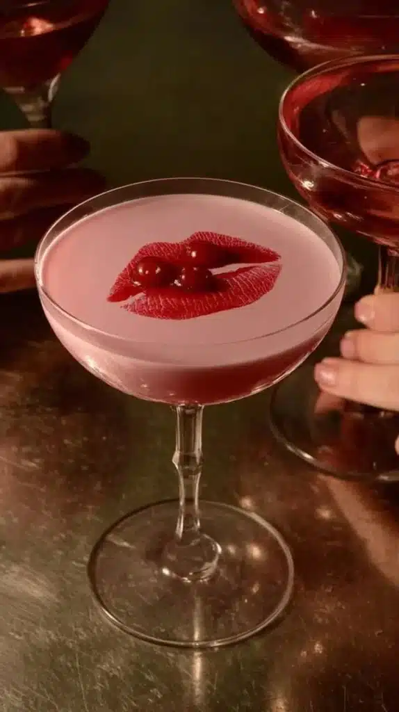 Image of a Pink Squirrel cocktail garnished with cherry and cream