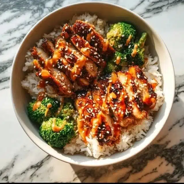 Delicious sticky chicken rice bowl with vibrant vegetables and savory sauce.