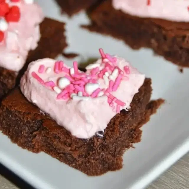 Home 5 Strawberry frosted heart-shaped brownies on a plate